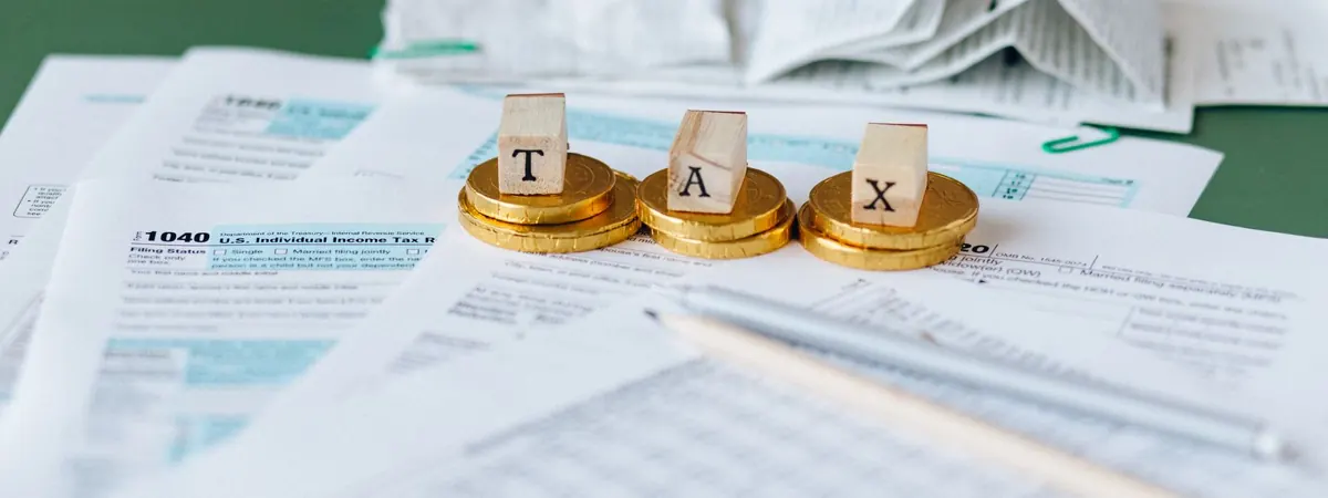Letter blocks spelling TAX on tax forms with coins