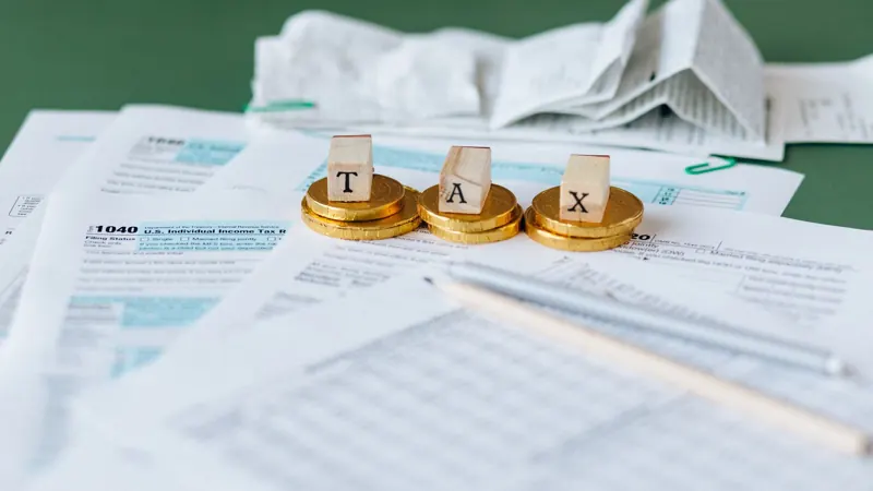 Letter blocks spelling TAX on tax forms with coins